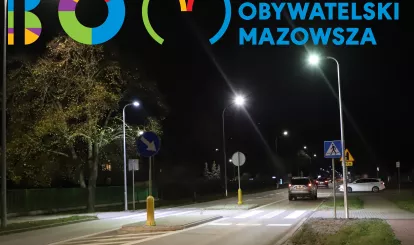 Zdjęcie przedstawia oświetlone przejście dla pieszych z logotypem Budżetu Obywatelskiego Mazowsza